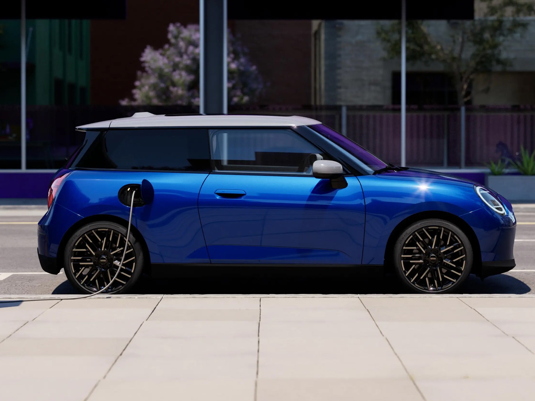 Side View of Blazing Blue all-electric MINI Cooper parked on pavement beside a charging station